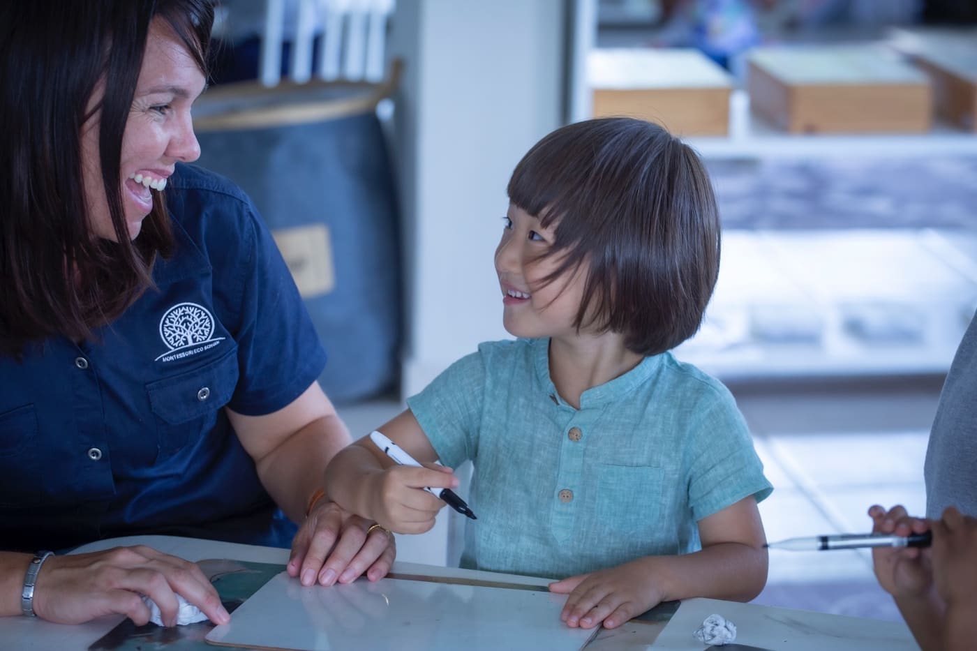 A teacher laughing with children at Montessori Eco Schools